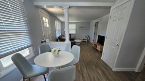 A modern dining area with a round table, four chairs, and a vase of flowers. - Cozy 3 Bedroom Cottage in Charlestown (Charlestown)