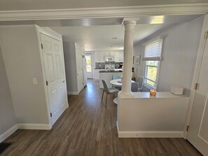A spacious kitchen with white cabinets, a central island, and a dining area with chairs. - Cozy 3 Bedroom Cottage in Charlestown (Charlestown)