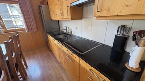 Eine Küche mit Holzausstattung, einer schwarzen Arbeitsplatte und einem Edelstahl-Spülbecken.