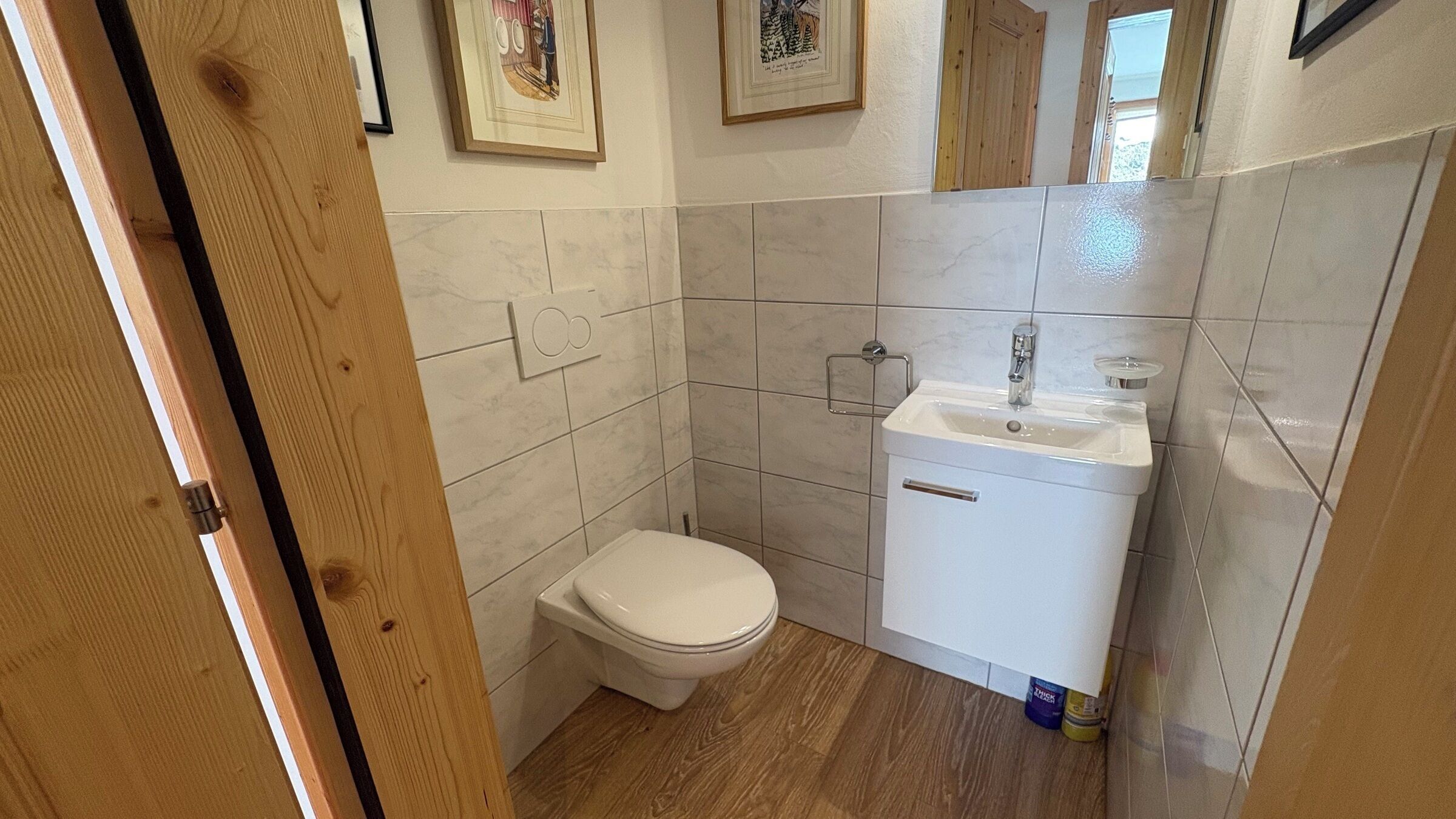Une petite salle de bain avec des toilettes, un lavabo et un plancher en bois.