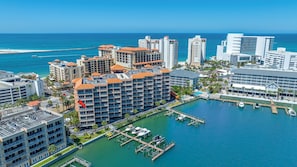 A high-rise hotel with multiple balconies, a marina with boats, and a clear view of the ocean.