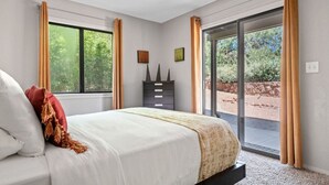 A bedroom with a bed, a dresser, and a sliding glass door leading to an outdoor area.