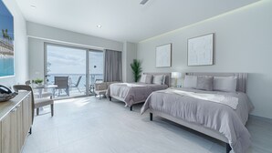 Une chambre d’hôtel moderne avec deux lits, un balcon offrant une vue agréable, un coin repas et un bureau.