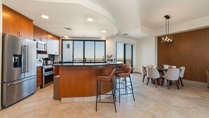A modern kitchen with a central island, bar stools, and a dining area with a view. - Stunning 3BR 3BA Cortez 601 @ Las Palomas Phase 2 (Puerto Peñasco)