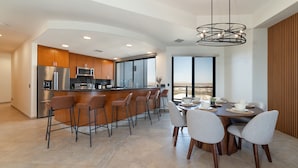A modern kitchen with a bar area, dining table with chairs, and a large window offering a view. - Stunning 3BR 3BA Cortez 601 @ Las Palomas Phase 2 (Puerto Peñasco)