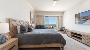 Habitación de hotel moderna con una cama grande, un escritorio, una silla y vista al océano.