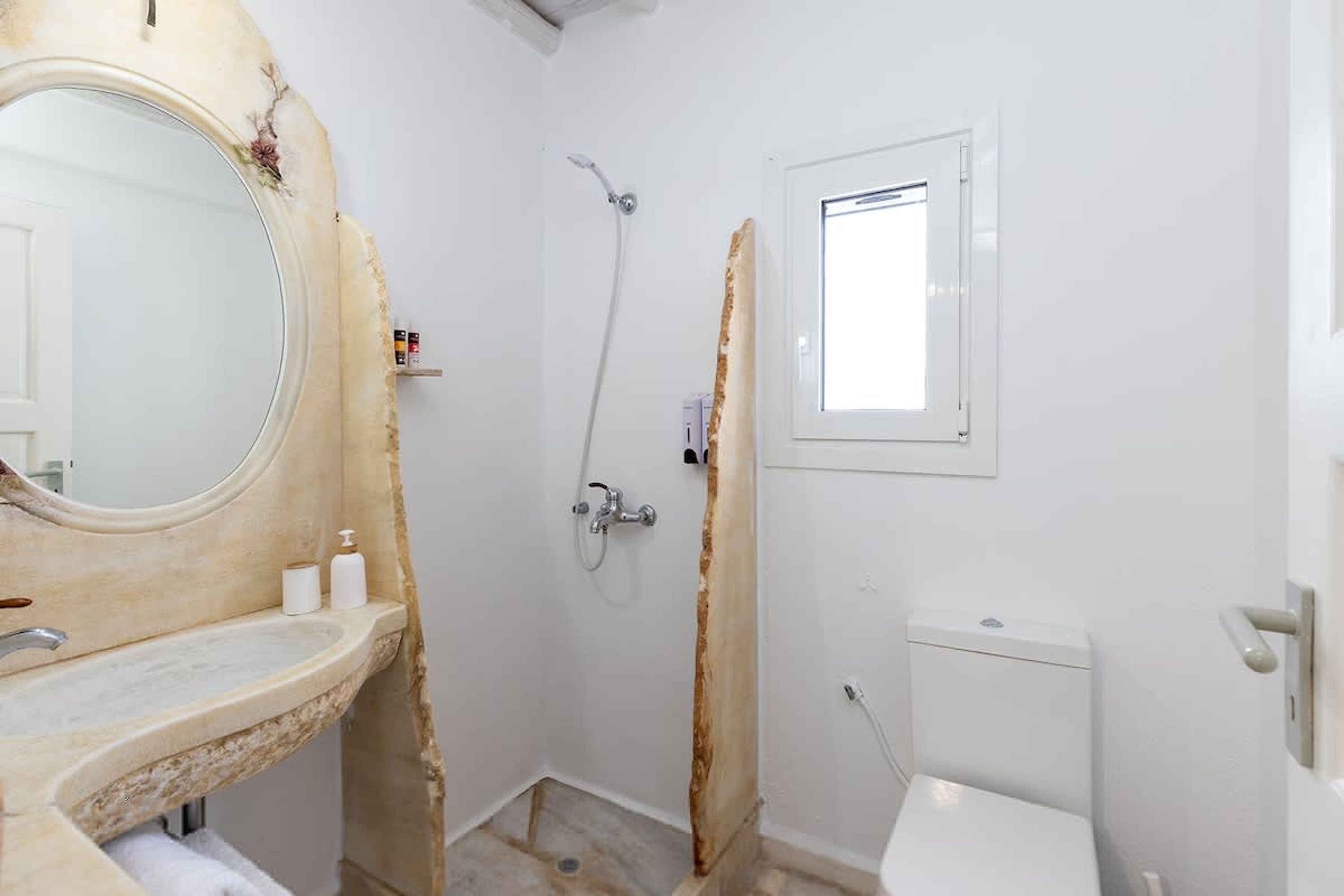 Un baño con lavamanos, espejo, ducha e inodoro.