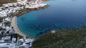 Vista aérea de un pueblo costero con edificios blancos, una playa y un mar azul cristalino.