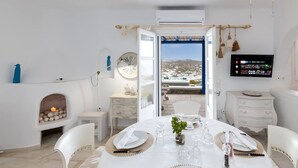 Un comedor con una mesa preparada para cuatro, chimenea, televisor y vista al paisaje.
