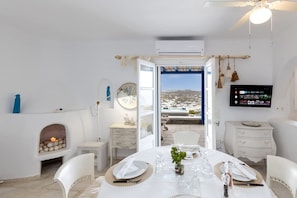 Ein Essbereich mit einem Tisch für vier Personen, einem Kamin, einem Fernseher und Blick auf die Landschaft.