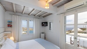 Un dormitorio con cama, televisor, ventana con vistas y puerta que da al exterior.