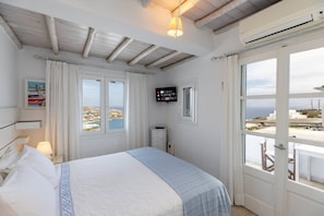 Ein Schlafzimmer mit einem Bett, einem Fernseher, einem Fenster mit Aussicht und einer Tür, die nach draußen führt.