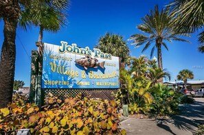 Schild für 'John's Pass' mit einem Fisch-Symbol, das einen Ort mit Einkaufsmöglichkeiten, Speisen und Wassersport kennzeichnet.