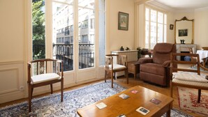 A room with a large window, a fireplace, a wooden table, and two chairs. - The Haussmann-style Sarcey - Welkeys (Paris)