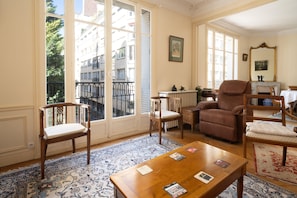 A room with a large window, a fireplace, a wooden table, and two chairs. - The Haussmann-style Sarcey - Welkeys (Paris)