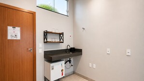 Cozinha compacta com geladeira embutida, pia e prateleira sobre a bancada.