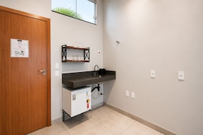 A compact kitchen with a built-in refrigerator, a sink, and a shelf above the countertop.