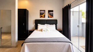A hotel room with a bed, a nightstand, a wardrobe, and two cityscape paintings on the wall.