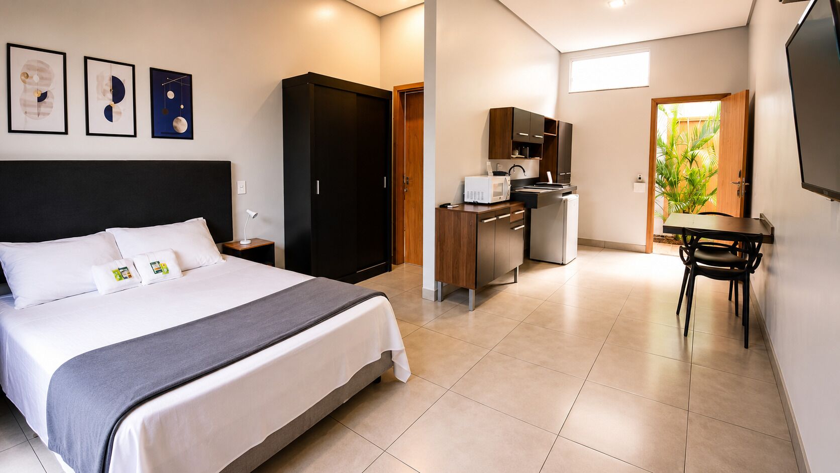 Een hotelkamer met een bed, een bureau, een kitchenette en een eethoek.