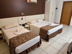 A hotel room with two beds, a nightstand, a telephone, a wardrobe, and a door. - Le Jardin Suites - Caldas Novas (Caldas Novas)