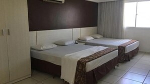 A hotel room with two beds, a wardrobe, an air conditioning unit, and a window with curtains. - Le Jardin Suites - Caldas Novas (Caldas Novas)