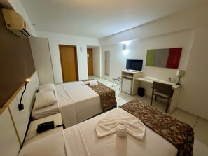 Una habitación de hotel con dos camas, un escritorio, un televisor y una silla.