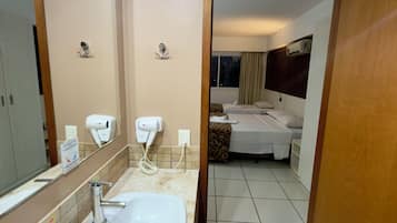 Un baño de hotel con lavamanos, secador de manos y espejo.