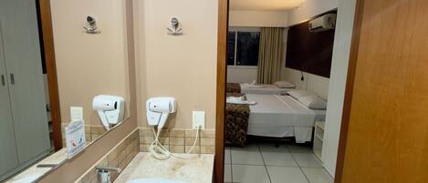 A hotel bathroom with a sink, hand dryer, and a mirror.