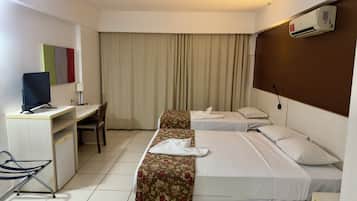 Una camera d'albergo con due letti, una scrivania con un computer, una sedia e un condizionatore d'aria.