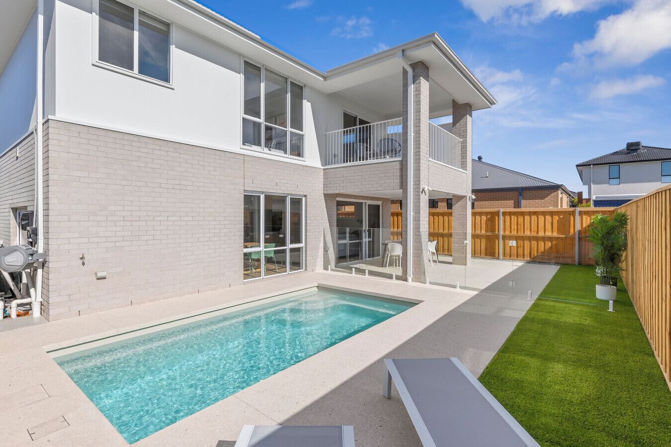Ein zweistöckiges Haus mit Swimmingpool, einem eingezäunten Garten und einem Holzzaun.
