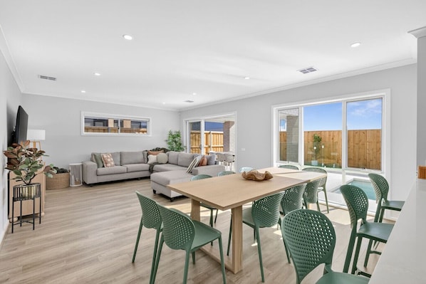 A modern living room with a sofa, dining table, chairs, and a TV.