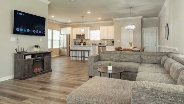 A modern living room with a sectional sofa, a flat-screen TV, and a fireplace. - Brand New 3BR - Patio - Fast WiFi+Workspace - Near Airport & Whitewater Center (Charlotte)