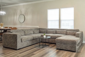 Un canapé modulable, une petite table ronde avec une plante, et un coin repas avec des chaises et une table.