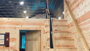 Ein Holzinnenraum mit einer Treppe, einer Tür und einem kleinen Tisch mit einer Lampe.