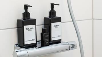 Two black bottles of Dusch Gel and Noir shampoo on a metallic shelf.