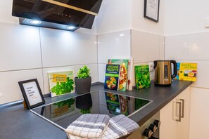 A modern kitchen with a glass countertop, a kettle, a framed quote, and various cookbooks. - Charmante Wohnung in Koblenz (Koblenz)