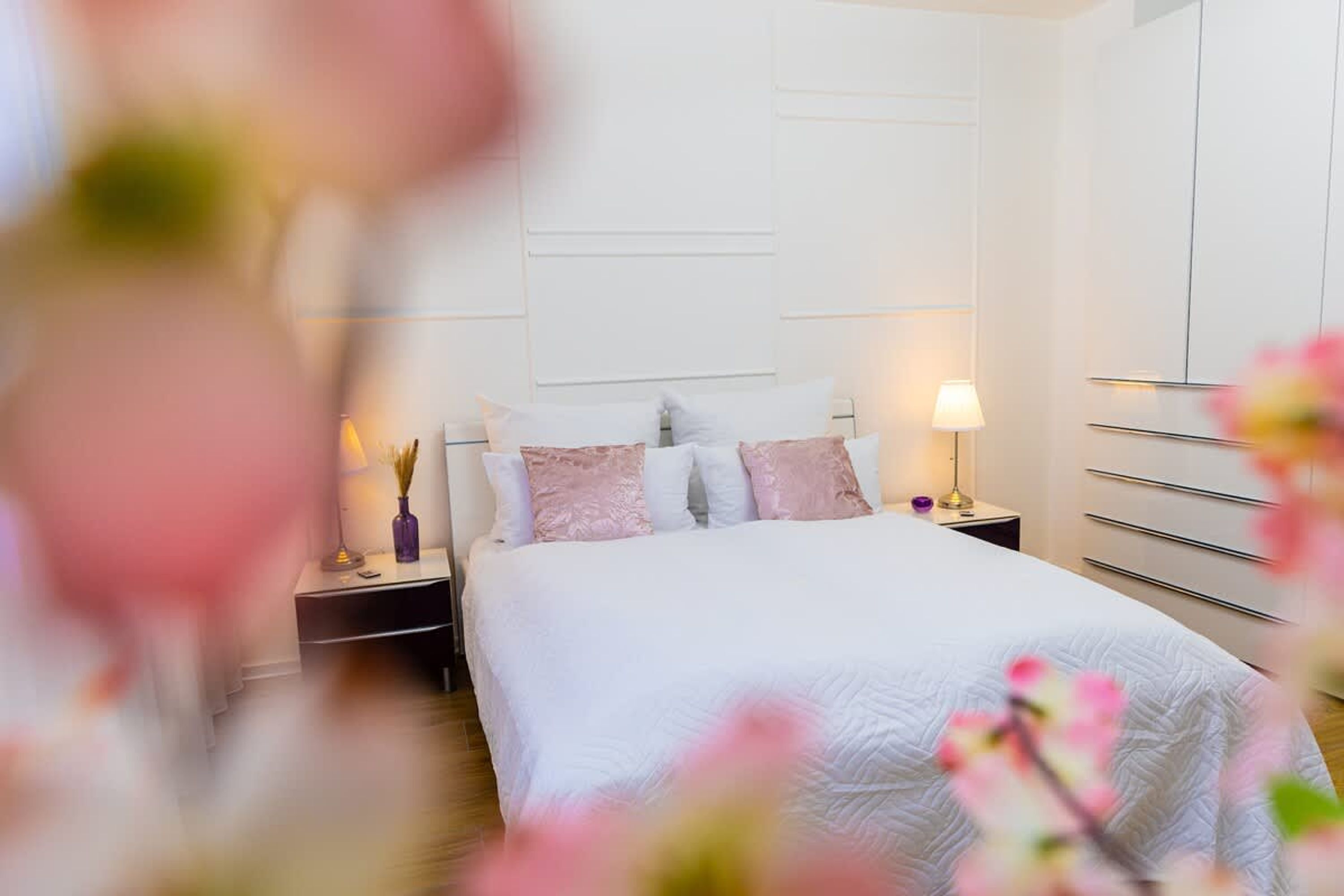 A bedroom with a bed, nightstands, a lamp, and a wardrobe.