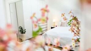 A bedroom with a bed, bedside table, lamp, and a potted plant. - Charmante Wohnung in Koblenz (Koblenz)
