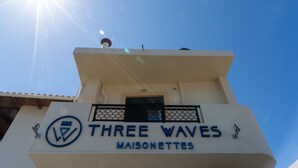 A hotel sign with the name 'THREE WAVES MAISONETTES' and a logo. - Three Waves Maisonettes (Agios Nikolaos)