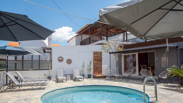 A swimming pool with lounge chairs, umbrellas, and a wooden deck. - Three Waves Maisonettes (Agios Nikolaos)