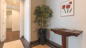 A hallway with a potted plant, a framed artwork, and a small table with a tray. - La Belle Vie by Atlantic Holiday (Funchal)