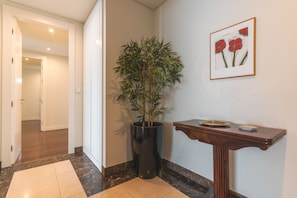 A hallway with a potted plant, a framed artwork, and a small table with a tray. - La Belle Vie by Atlantic Holiday (Funchal)