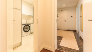A hotel hallway with a washing machine, a door with an emergency exit sign, and a marble-tiled floor. - La Belle Vie by Atlantic Holiday (Funchal)