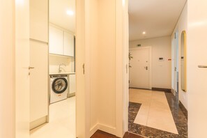 A hotel hallway with a washing machine, a door with an emergency exit sign, and a marble-tiled floor. - La Belle Vie by Atlantic Holiday (Funchal)