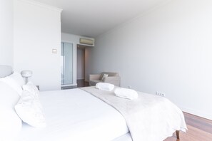 Een slaapkamer met een bed, nachtkastje en een stoel.