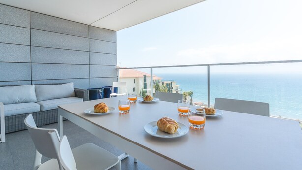 A modern dining area with a balcony overlooking the sea, featuring a table set with croissants and orange juice glasses. - La Belle Vie by Atlantic Holiday (Funchal)