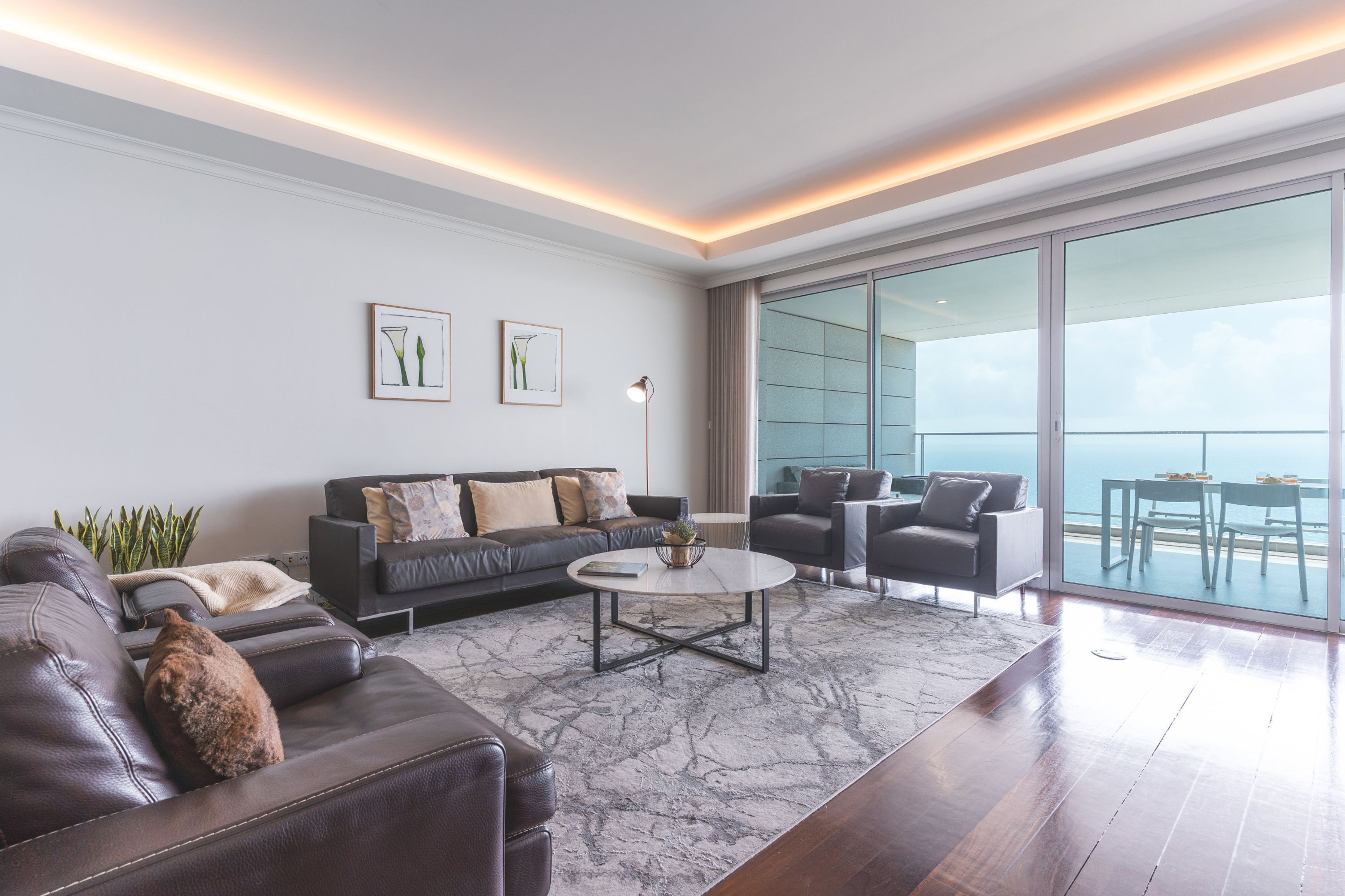 A modern living room with a sofa, armchairs, a coffee table, and a large window with a view.