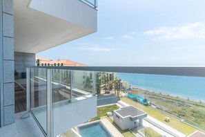 Een modern gebouw met een glazen balkon dat uitkijkt over een zwembad en de zee.