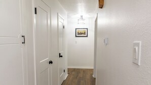 Ein Korridor mit weißen Wänden, Holzdielen und einem gerahmten Bild an der Wand.