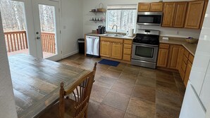 Eine Küche mit Holzausstattung, einem Edelstahlbackofen, einer Mikrowelle und einem Essbereich mit Tisch und Stühlen.
